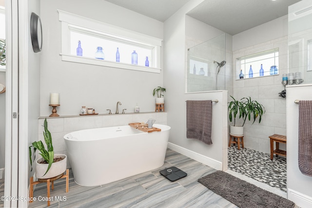 bathroom with tile walls, shower with separate bathtub, and wood-type flooring