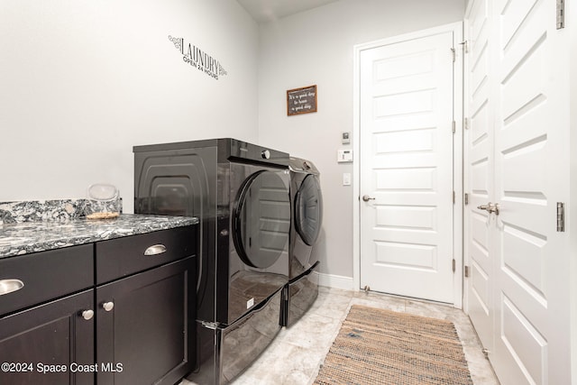 clothes washing area with cabinets and washer and clothes dryer