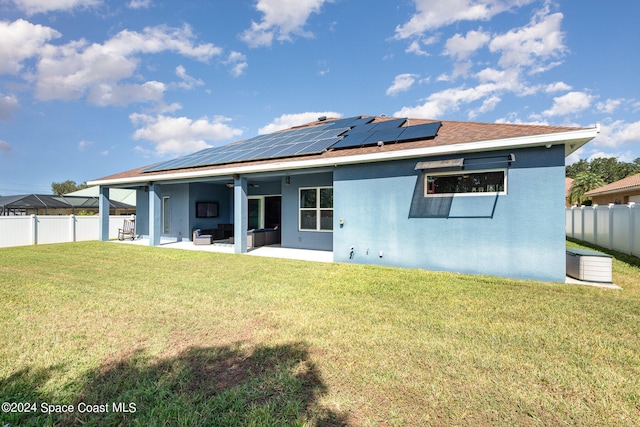 back of property with a yard, a patio, and solar panels