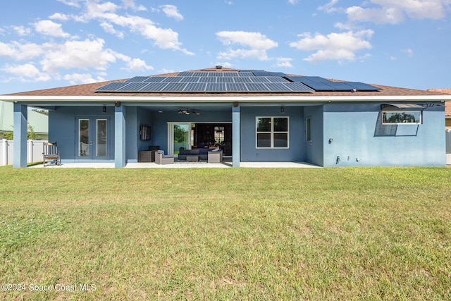 back of house with a yard, an outdoor living space, and solar panels