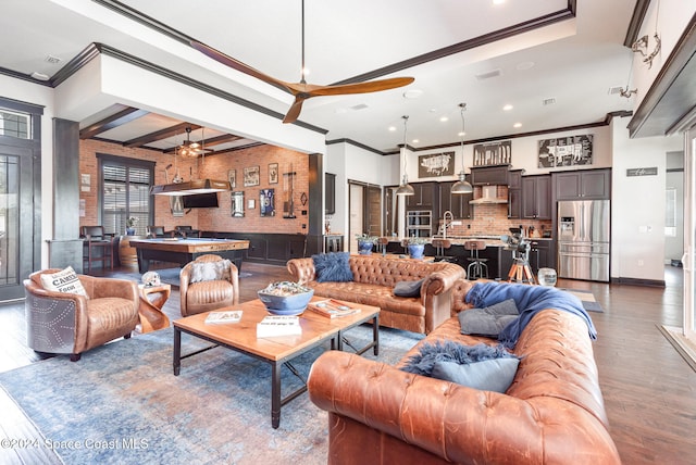 living room with hardwood / wood-style floors, ceiling fan, ornamental molding, beamed ceiling, and sink