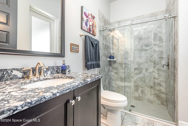 bathroom featuring vanity, toilet, walk in shower, and tile patterned flooring