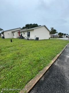 view of side of home with central AC and a yard