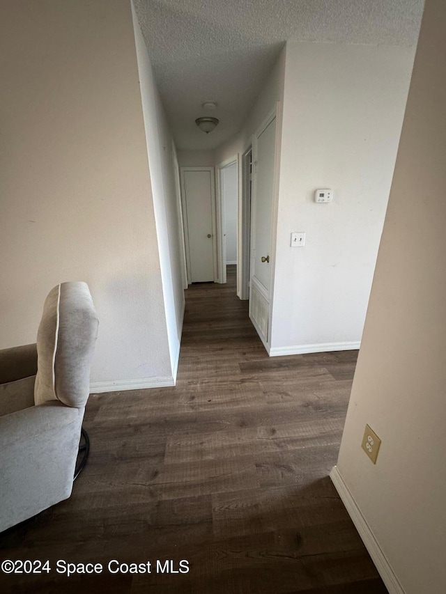 corridor with dark hardwood / wood-style floors and a textured ceiling