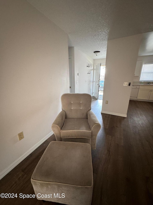 living area with a textured ceiling and dark hardwood / wood-style flooring