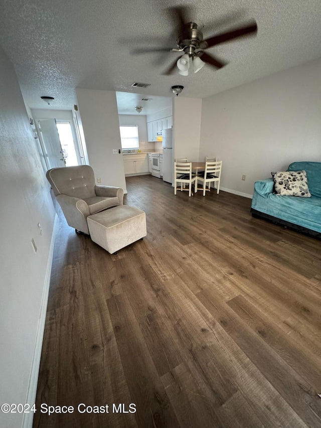 unfurnished living room featuring a textured ceiling, dark wood-type flooring, and ceiling fan