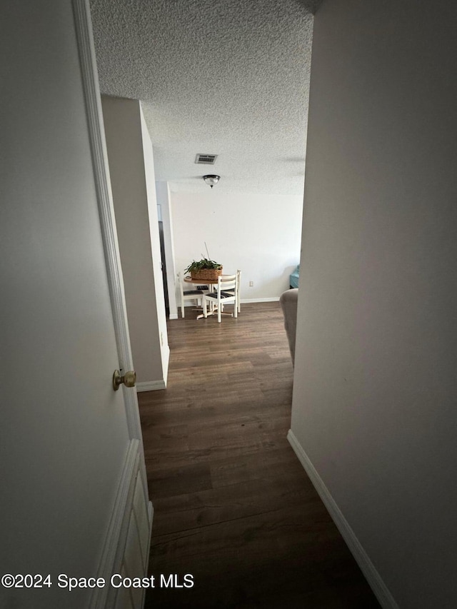 corridor featuring dark hardwood / wood-style floors and a textured ceiling