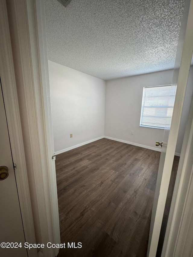 empty room featuring dark hardwood / wood-style floors and a textured ceiling