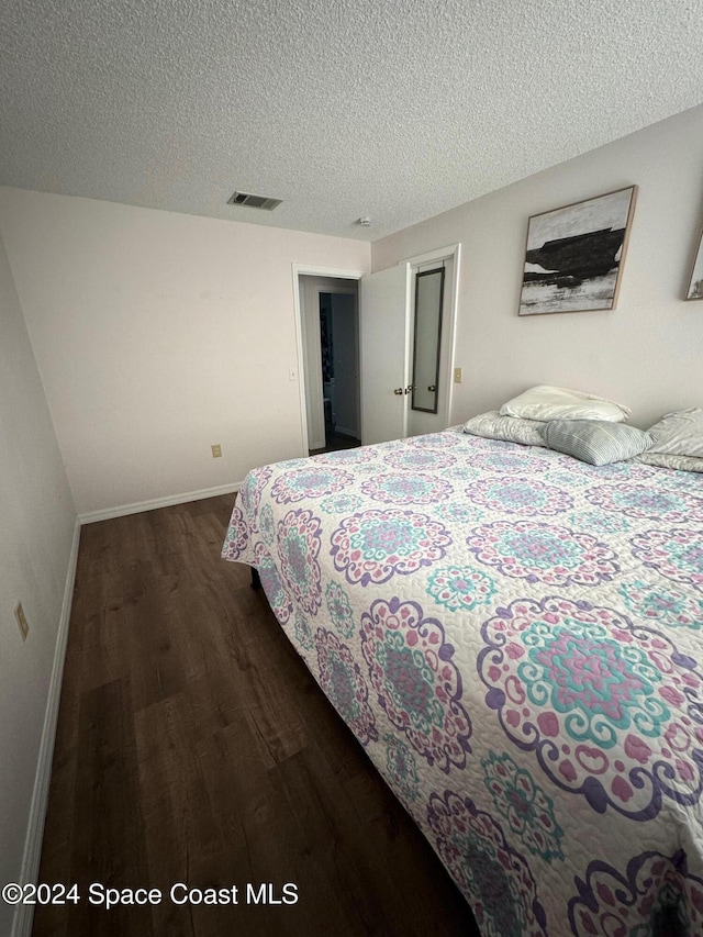 bedroom featuring a textured ceiling and dark hardwood / wood-style flooring