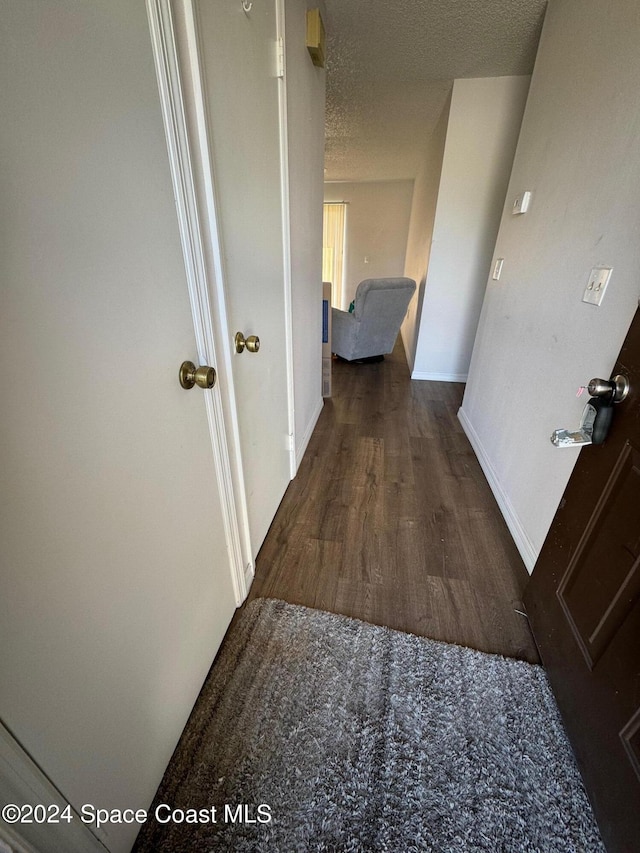 hallway with dark hardwood / wood-style floors and a textured ceiling