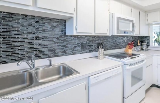 kitchen featuring white cabinets, sink, backsplash, and white appliances