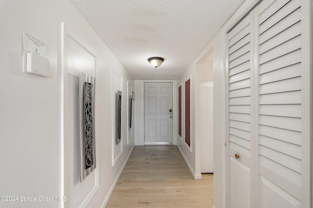 corridor featuring light hardwood / wood-style flooring and a textured ceiling