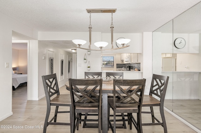 dining area featuring light hardwood / wood-style floors, a textured ceiling, and a chandelier