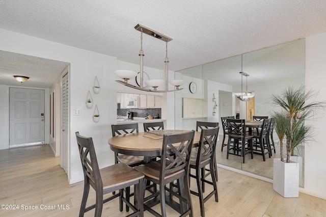 dining room featuring a notable chandelier, a textured ceiling, and light hardwood / wood-style flooring