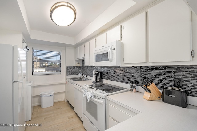 kitchen featuring sink, white cabinets, decorative backsplash, and white appliances