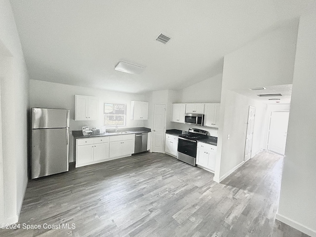 kitchen with white cabinets, sink, vaulted ceiling, light hardwood / wood-style floors, and stainless steel appliances