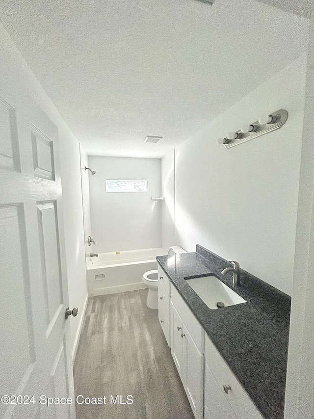 full bathroom featuring shower / bathtub combination, vanity, a textured ceiling, hardwood / wood-style floors, and toilet