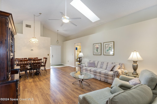 living room featuring ceiling fan, hardwood / wood-style flooring, high vaulted ceiling, and a skylight