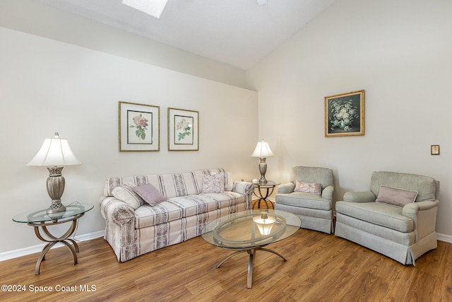 living room featuring lofted ceiling with skylight and hardwood / wood-style flooring