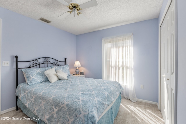 bedroom with light carpet, a textured ceiling, a closet, and ceiling fan