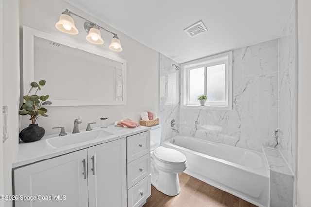 full bathroom featuring vanity, toilet, tiled shower / bath combo, and hardwood / wood-style floors