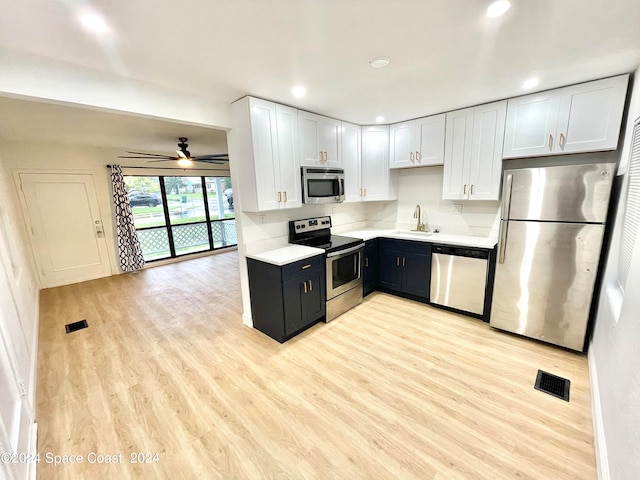 kitchen featuring light wood-type flooring, ceiling fan, white cabinets, sink, and appliances with stainless steel finishes