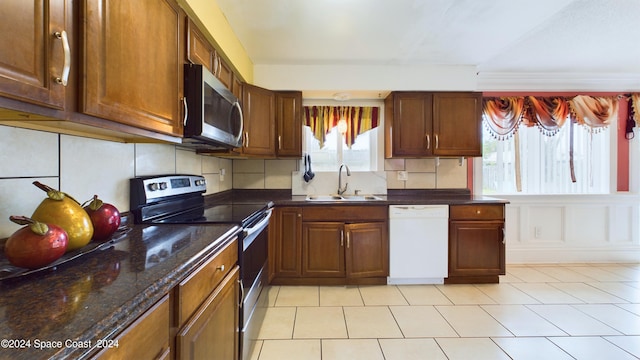 kitchen with dark stone countertops, stainless steel appliances, sink, and tasteful backsplash