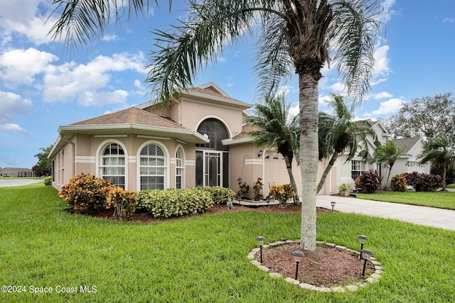 4889 Worthington Cir, Rockledge, FL 32955 - mediterranean / spanish-style house with concrete driveway, an attached garage, stucco siding, and a front yard
