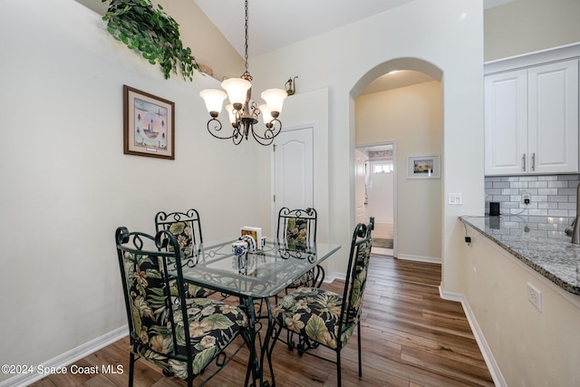 4889 Worthington Cir, Rockledge, FL 32955 - dining area featuring lofted ceiling, baseboards, an inviting chandelier, wood finished floors, and arched walkways