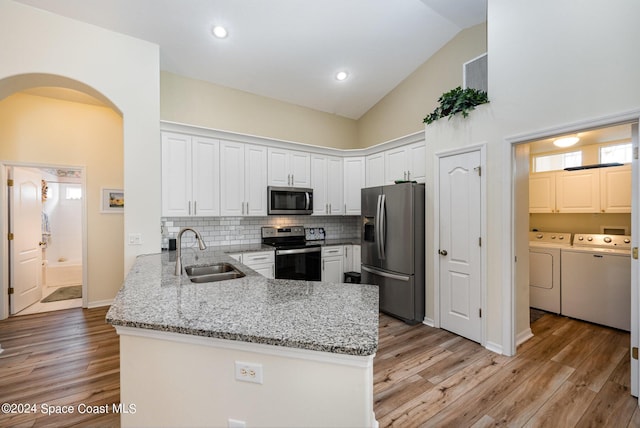 4889 Worthington Cir, Rockledge, FL 32955 - kitchen with washer and clothes dryer, a peninsula, stainless steel appliances, a sink, and high vaulted ceiling
