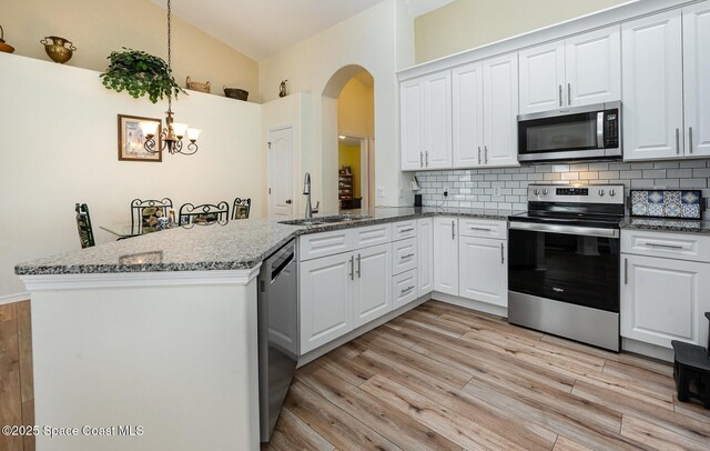 4889 Worthington Cir, Rockledge, FL 32955 - kitchen with a peninsula, a sink, stainless steel appliances, arched walkways, and backsplash