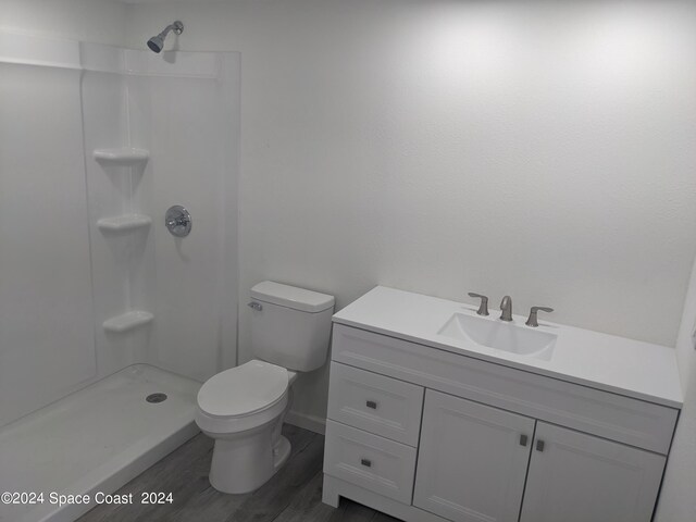 bathroom featuring toilet, walk in shower, vanity, and hardwood / wood-style flooring