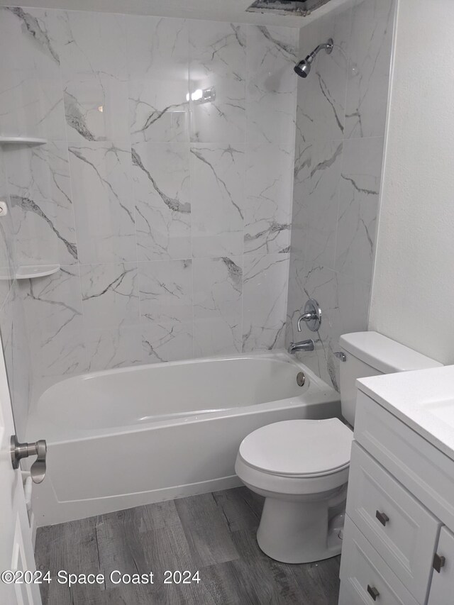 full bathroom with tiled shower / bath, vanity, wood-type flooring, and toilet