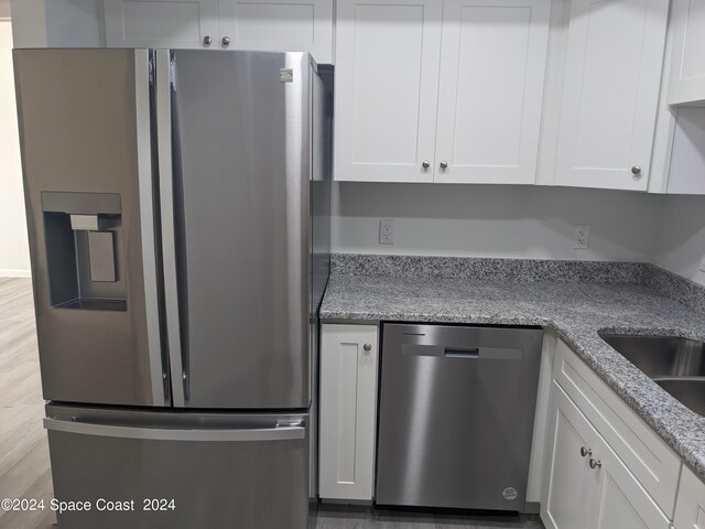 kitchen with light hardwood / wood-style flooring, white cabinetry, light stone countertops, and stainless steel appliances