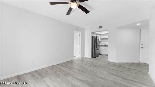 unfurnished living room with light hardwood / wood-style flooring, sink, and ceiling fan