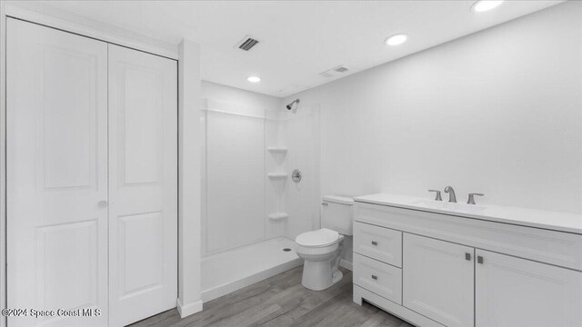 bathroom featuring hardwood / wood-style floors, vanity, a shower, and toilet