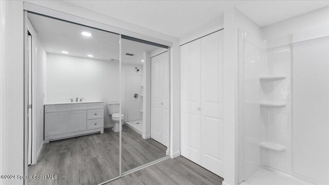 bathroom with toilet, walk in shower, vanity, and wood-type flooring