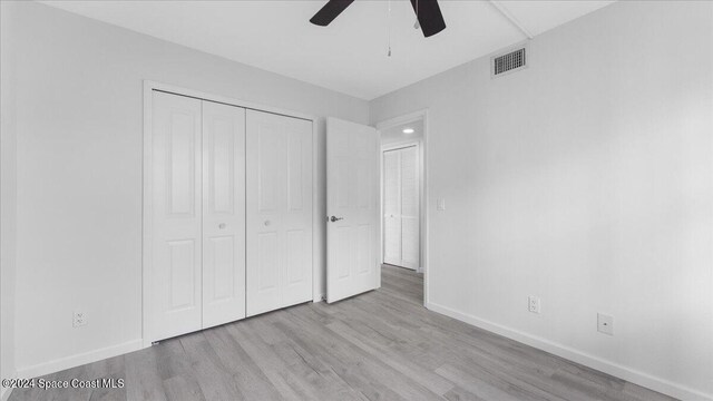 unfurnished bedroom featuring a closet, light hardwood / wood-style floors, and ceiling fan