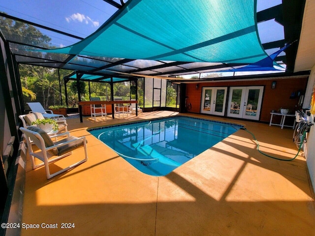 view of pool with french doors, glass enclosure, and a patio area