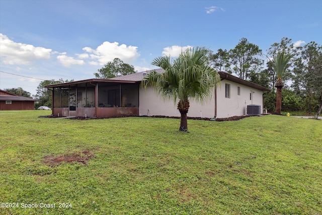 back of house featuring a sunroom, a yard, and central air condition unit