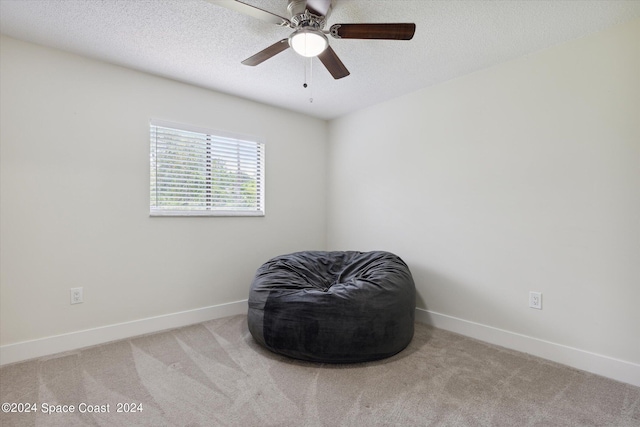 sitting room featuring light carpet, ceiling fan, and a textured ceiling