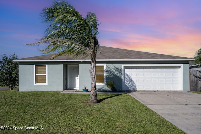 ranch-style home featuring a garage and a lawn