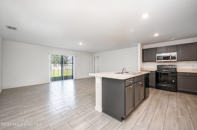 kitchen featuring black appliances, sink, and an island with sink