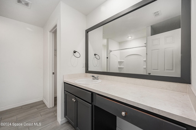 bathroom with vanity, a shower, and wood-type flooring