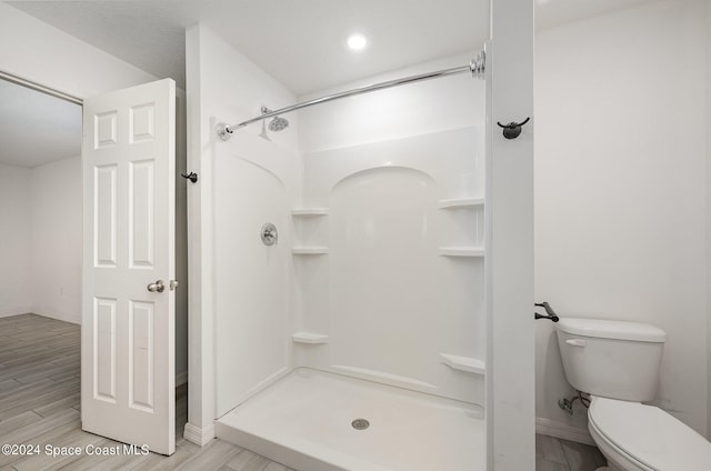 bathroom featuring toilet, hardwood / wood-style floors, and a shower