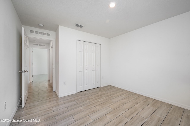 unfurnished bedroom featuring a closet, a textured ceiling, and light wood-type flooring