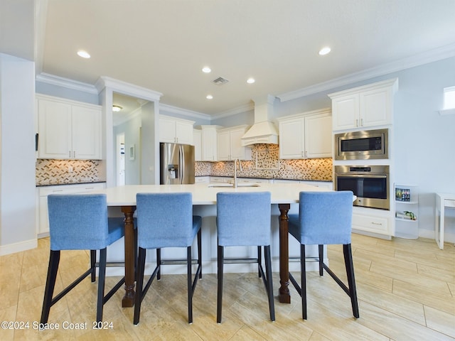 kitchen with premium range hood, sink, white cabinetry, a large island, and appliances with stainless steel finishes