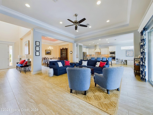 living room with ceiling fan with notable chandelier, crown molding, and a raised ceiling