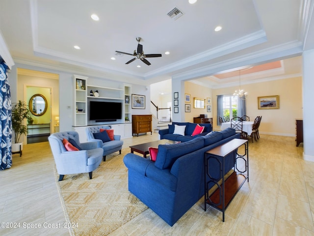 living room with ceiling fan with notable chandelier, crown molding, and a tray ceiling