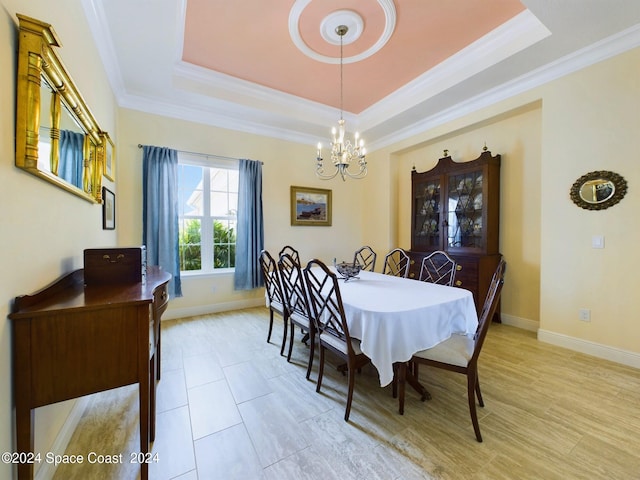 dining room with a raised ceiling, crown molding, and a notable chandelier